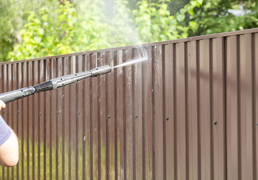 man power washing the metal fence
